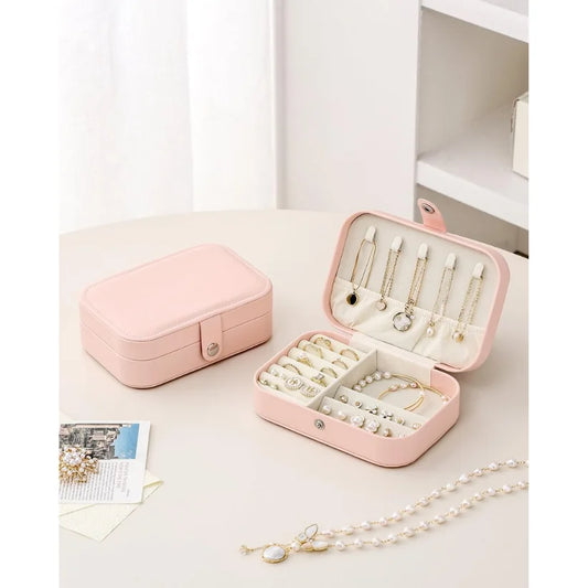 Pink jewelry case with jewelry on a white surface